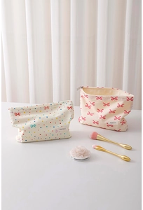 Close-up of canvas makeup bags with bow patterns and zipper details on white surface