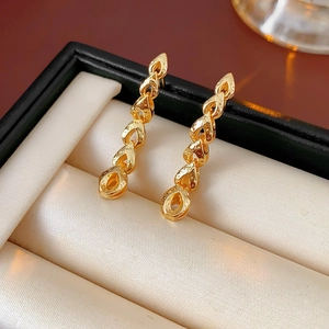 Détail des boucles d'oreilles pendantes en forme d'épi de blé doré dans un coffret noir