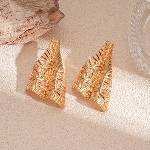 Vue détaillée de boucles d'oreilles dorées irrégulières avec texture froissée mate