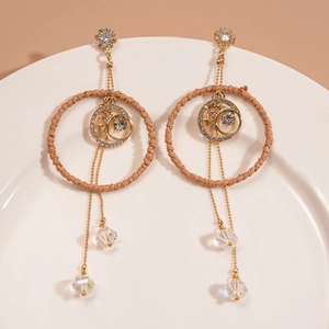 Detail view of gold tassel earrings with woven ring, star-moon motif and crystal drops
