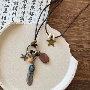 Détail d'un collier bohème vintage avec plumes en métal, étoile de mer et perles en bois