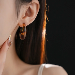 Close-up of leopard print resin C-shaped hoop earrings worn by a model