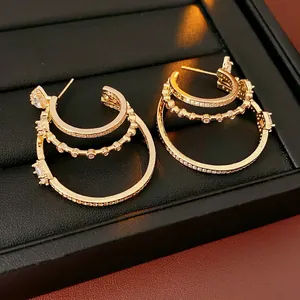 Three-layer gold C-shaped earrings with rhinestones on black leather display case