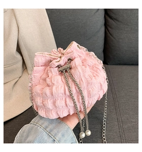 Detail of pink pleated chain bag with silver metal strap and elegant pearl pendant accessory