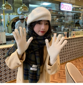 Close-up of cream knit touch-screen gloves paired with a green and blue plaid winter scarf
