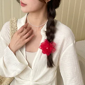 Barrette fleur rose romantique en organza rouge sur une coiffure avec tresse