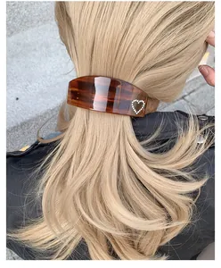 Macro detail of French amber heart hair clip with rhinestones on blonde wavy hair