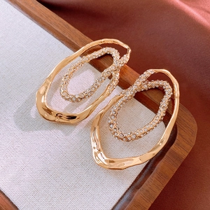 Detailed view of gold-plated hoop earrings with sparkling rhinestones on fabric background