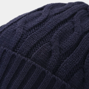 Close-up of deep blue cable knit beanie showing thick woolen texture and ribbed edge