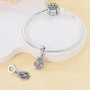 Close-up of silver snake chain bracelet with colorful harp and butterfly enamel charms