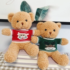Pair of brown teddy bears in Christmas sweaters sitting on books for holiday gifting