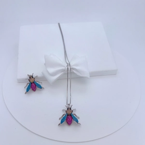 Detailed view of a silver bee pendant with vibrant blue and pink zircon stone inlay