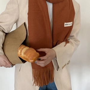 Caramel cashmere-feel scarf with fringes and 'different' label on beige blazer