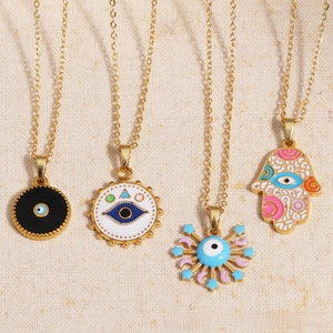 Detail showing four different gold Evil Eye and Hamsa Hand pendant necklaces with enamel