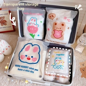 Detail showing multiple sizes of cute cartoon travel storage bags inside a suitcase