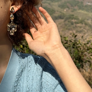 Close-up of champagne teardrop tassel earrings with sparkling crystals worn by a model