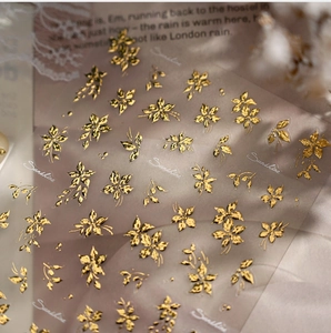Close-up of golden floral nail art stickers with embossed metallic texture and flower patterns