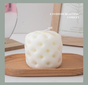 Detail of white geometric pillar candle with tufted texture on a wooden oval tray