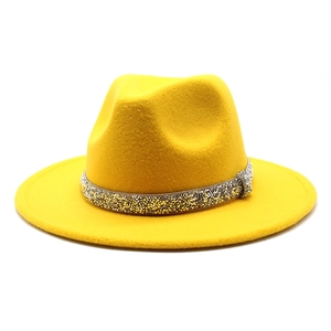 Detail of a bright yellow fedora hat featuring a sparkling gold and silver crystal band
