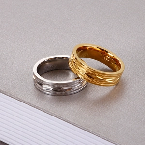 Close-up of gold and silver titanium rings with geometric textures on textured surface