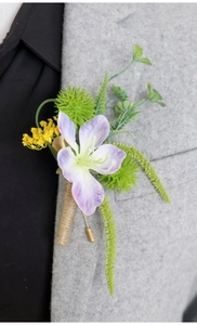 Close-up of lavender silk boutonniere with fern leaves on gray wool suit lapel