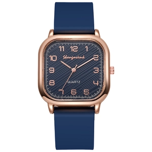 Detailed close-up of rose gold square watch case with blue textured dial and silicone strap