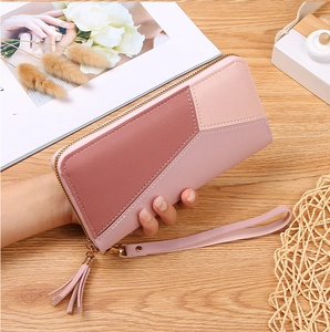 Detailed close-up of a pink geometric patchwork long wallet with a tassel and wrist strap