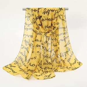 Écharpe légère en mousseline jaune avec imprimé texte noir drapée sur barre métal