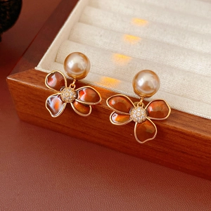 Détail des boucles d'oreilles fleur en perle champagne avec émail orange et zircons