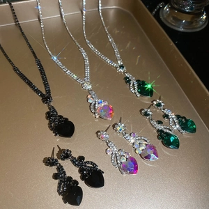 Detail of luxury flower and heart jewelry sets with crystals in black, green, and clear colors