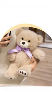 Close-up of fluffy plush teddy bear with a purple polka dot bow tie in a warm embrace