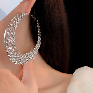 Macro shot of large silver hoop earrings with sparkling rhinestones on a female model