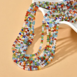 Detail of 3mm pastel multifaceted glass beads draped over a white wavy ceramic display plate