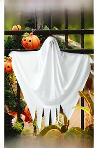 Close-up of a white fabric Halloween ghost hanging on a black iron fence with pumpkins