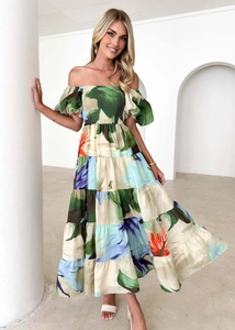 Detail of off-shoulder floral dress with tiered skirt and tropical prints on beige fabric