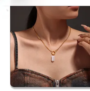 Close-up of a 18k gold plated necklace with a baroque pearl pendant on a model