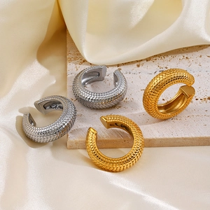 Fish scale textured ear cuffs in gold and silver finish on a travertine stone plate