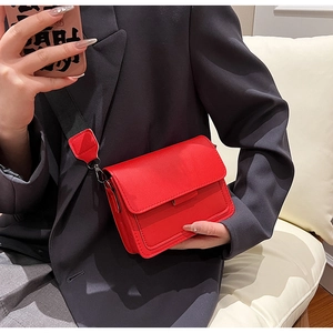 Crossbody view of a vibrant red patent leather square bag with a matching wide strap