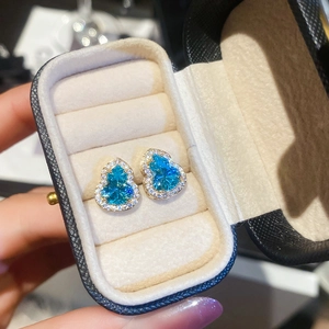 Détail de boucles d'oreilles gourde avec pierres bleues en cœur et micro-pavé de cristaux