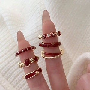 Detail view of vintage red enamel flower ring set with gold finish on fingers