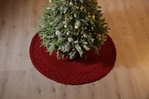 Détail du tapis de sapin de Noël tricoté rouge avec motif losanges sur parquet