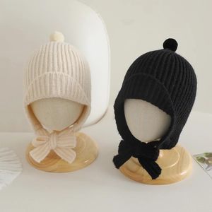 Détail de bonnets en tricot pour enfants avec pompons décoratifs et liens à nouer