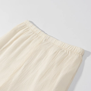 Detailed close-up of cream textured chiffon dress with elastic waistband and pleated fabric