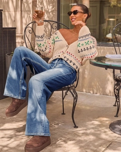Outdoor streetstyle look met blauwe flared jeans met hoge taille en gebreid vest