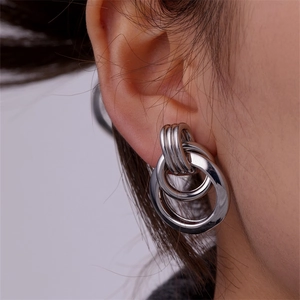 Macro shot of silver triple-linked thick round earrings worn on a model for a modern look