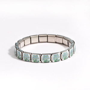 Macro shot of stainless steel modular link featuring a blue flower enamel design