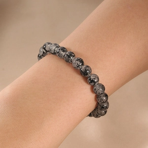 Close-up of snowflake obsidian beaded bracelet worn on a wrist with natural stone textures