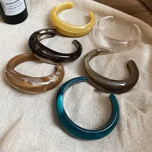 Acrylic geometric open bangles in diverse colors with marble texture on linen surface
