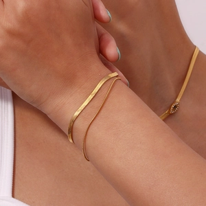 Close-up of double-layer gold snake chain bracelets styled on a woman's wrist
