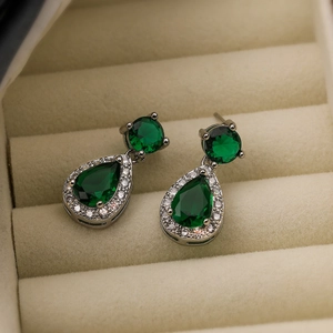 Macro shot of silver drop earrings with green stones and sparkling zircon borders